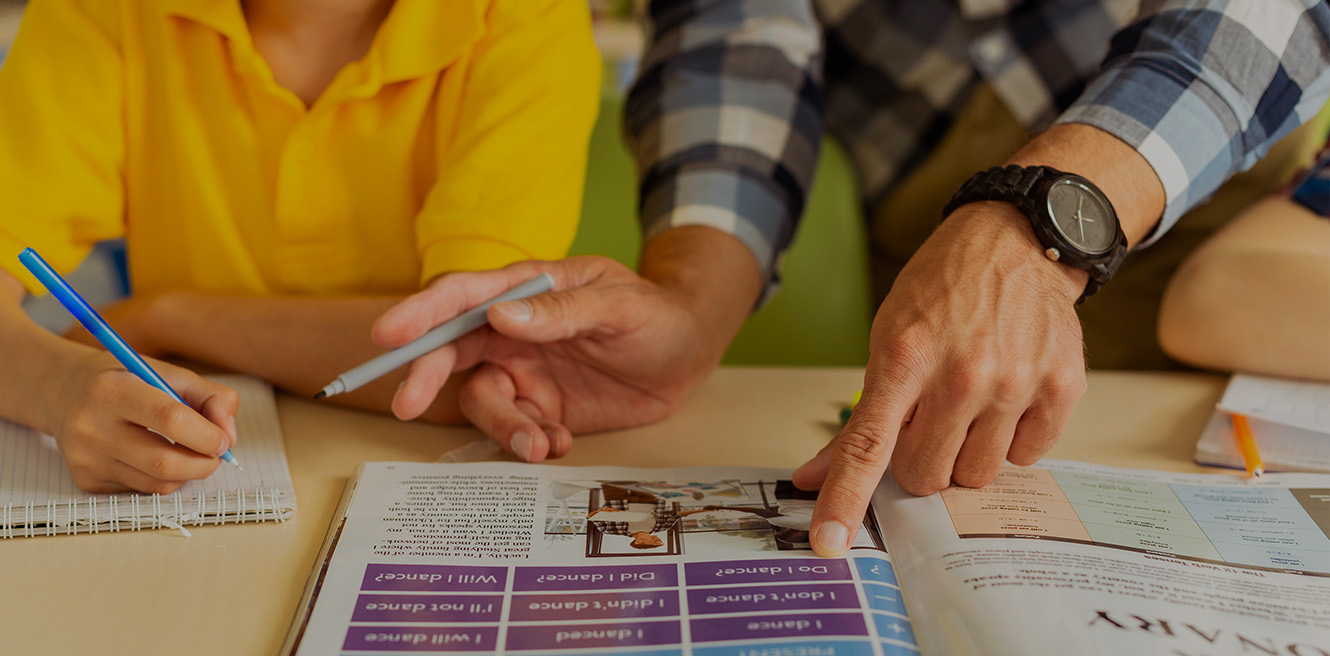 Male tutor working with student in English book